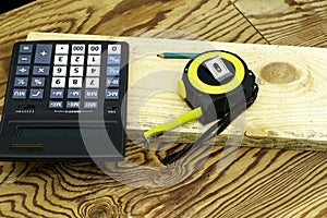 Construction meter-tape measure calculator for calculations pencil and wooden board are on the workbench