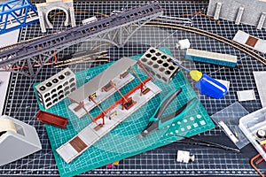 Construction of model railroad layout. workbench with model railway train station bridge tracks and landscape tools. hobby leisure