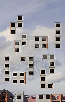 Construction of multi-storey building. Building house in form of tetris on blue sky background.