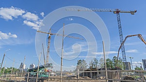 Construction of a multi-story residential buildings. Defocused foreground with young tree. Cranes work. Construction site