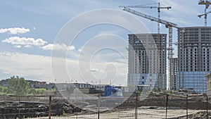 Construction of a multi-story residential buildings. A lot of construction equipment, cranes work. Construction site