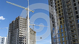 Construction of a multi-story residential buildings. A lot of construction equipment, cranes work. Construction site