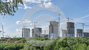 Construction of a multi-story residential buildings. A lot of construction equipment, cranes work. Construction site