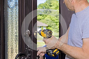 During the construction of the new home, a carpenter worker installs a new lock on the front door