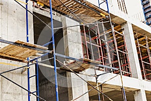 Construction of a new monolithic reinforced concrete house. Scaffolding on the facade of a building under construction. Working at