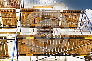 Construction of a new monolithic reinforced concrete house. Scaffolding on the facade of a building under construction. Working at
