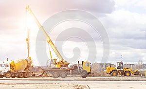 Construction of a new road and installation of lampposts using a truck crane and cement truck, workers, copy space, profession,