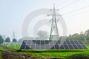 Construction of new solar power plant panels near high voltage power line, foggy weather