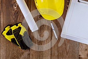 Construction office engineer working on rolls of architecture blueprints house plans working yellow helmet safety protective