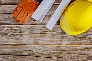 Construction office working with blueprints in the set of protective workwear in yellow hard hat protective gloves