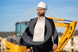 Construction owner near excavator. Confident construction owner in front of house. Architect, civil engineer. Man