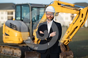 Construction owner near excavator. Confident construction owner in front of house. Architect, civil engineer. Man