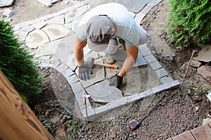 Construction of pavement near the house. Bricklayer places concrete paving stone blocks for building up a Sidewalk