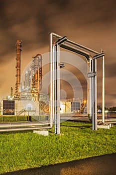 Construction with pipeline and Illuminated petrochemical production plant at twilight