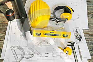 Construction plans with helmet and drawing tools on blueprints .