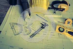 Construction plans with helmet and drawing tools on blueprints .