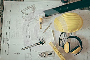 Construction plans with helmet and drawing tools on blueprints .