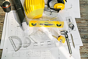 Construction plans with helmet and drawing tools on blueprints .