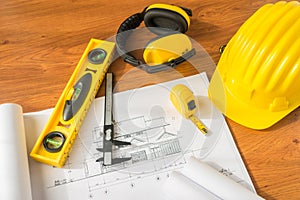 Construction plans with yellow helmet and drawing tools on blueprints .