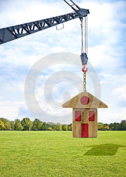 The construction of a prefabricated building - concept image with a tower crane holding a wooden house