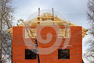 Construction of a private brick house with scaffolding at the base of the roof.