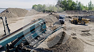 The construction process. Scene. Trucks carry materials for construction in an empty area behind which there is a river