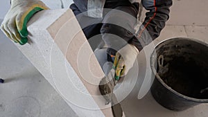 Construction worker applying cement on aerated concrete brick