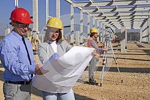 Construction Project Manager And Young Female Architect Checking The Blueprint On Construction Site