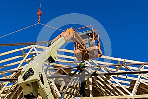 During the construction of the rafters of an unfinished wooden house, the crane holds the wood beams of the trusses to