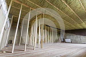 Construction and renovation of big spacious empty unfinished attic room with oak floor, walls and ceiling insulated with rock woo