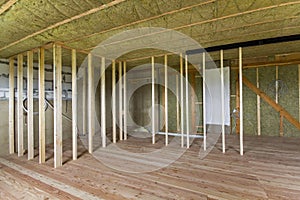 Construction and renovation of big spacious empty unfinished attic room with oak floor, walls and ceiling insulated with rock woo