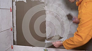 Construction repair tiler using tool and adhesive mixtures to prepare walls for laying ceramic tiles. Close-up of hand