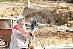 Construction of a residential area. Geodetic stakeout. Surveyor at a large construction site. A man with a tachometer during work photo