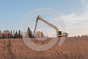 Construction of the road, an excavator on a mountain of sand