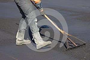 Construction road worker levelling fresh asphalt concrete photo
