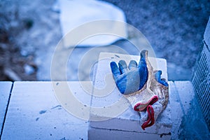 Construction rubberized worn glove lies on a white brick aerated block