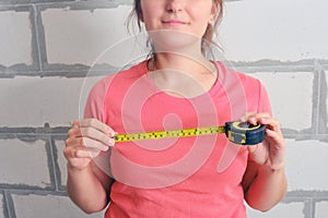 Construction ruler in the hands of a woman to check the length. Yellow tape measure for close-up. Measurements of the new