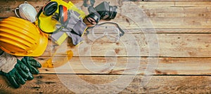 Construction safety. Protective hard hat, headphones, gloves and glasses on wooden background, banner
