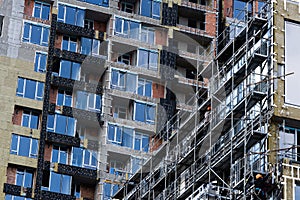 Construction of scaffolding and installation of glass facade panels against the backdrop of a new building