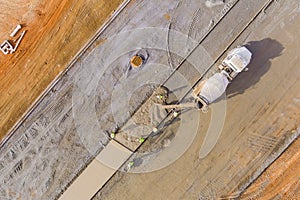 During the construction of a sidewalk, a concrete mix truck is pouring cement during the pouring of cement by workers