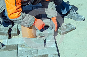 Construction of a sidewalk near the house. The bricklayer lays concrete paving stones for the device of a sidewalk path