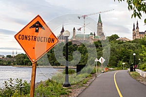 Construction sign on road and panoramic view of Ottawa River, Parliament Hill and Alexandra Bridge in Ottawa, Canada
