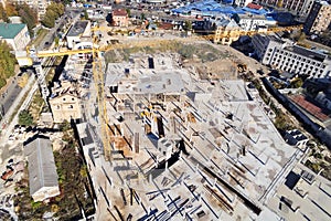 Construction site aerial view. Mall building base with solid concrete pillars. Heavy machinery and high tower crane