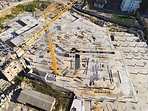 Construction site aerial view. Mall building base with solid concrete pillars. Heavy machinery and high tower crane