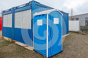 A construction site a blue construction site toilet stands next to a blue container