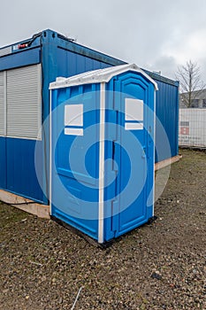 A construction site a blue construction site toilet stands next to a blue container