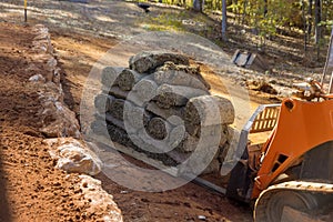 In a construction site, a boom lift is used to unload turf rolls from pallets for landscaping in order to lay green