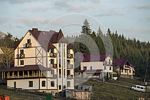 Construction site with building crane and new modern comfortable hotel house with shingled roof in ecological rural area on spruce photo