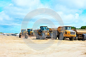 Construction site with bulldozers work trucks concrete pipes on cleared land on beautiful blue sky white clouds day