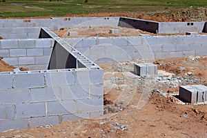 At a construction site, cement blocks support foundation for wall of house